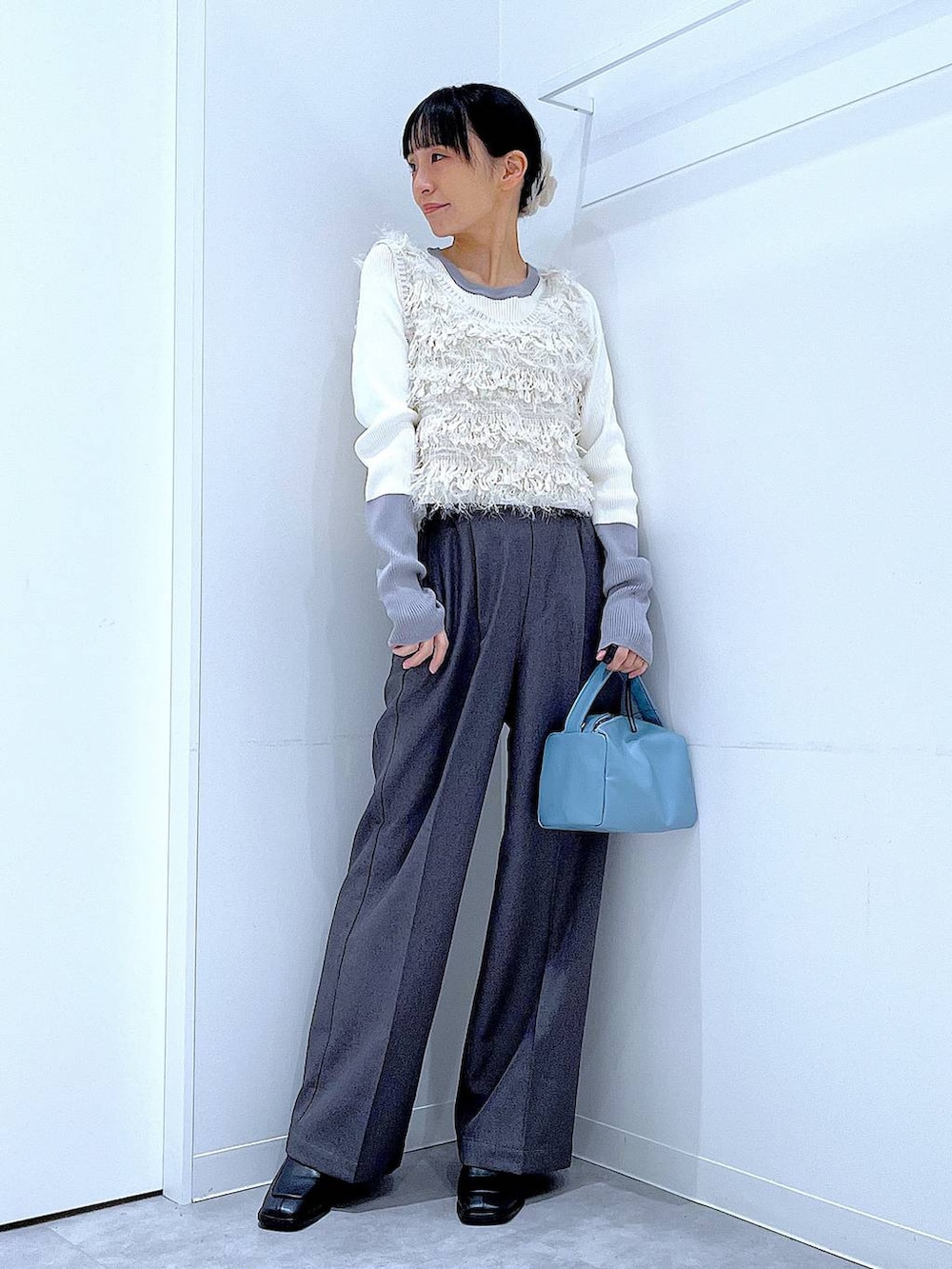 ブラック系のブーツ、グレー系のスラックス、ホワイト系のベストを着用したレディースの冬コーディネートの2枚目の写真