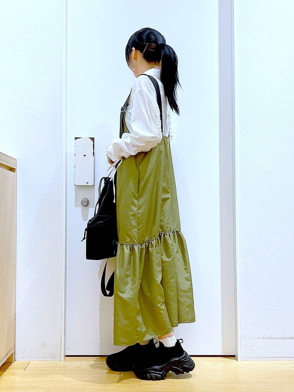 ブラック系のショルダーバッグ、グリーン系のワンピース、ホワイト系のシャツ/ブラウスを着用したレディースの春コーディネートの3枚目の写真