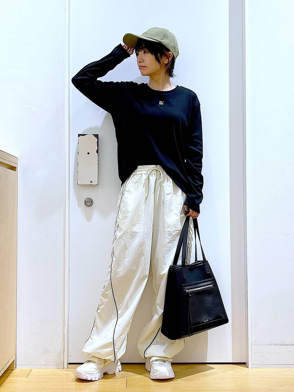 ホワイト系のスニーカー、ベージュ系のその他パンツ、ブラック系のトートバッグを着用したレディースの秋コーディネートの2枚目の写真