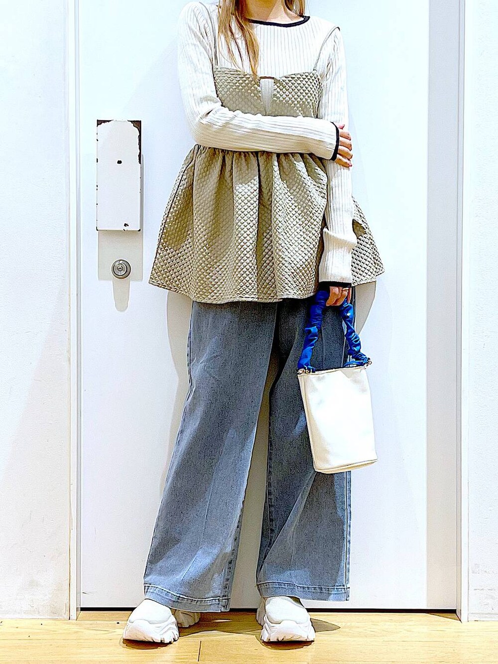 ブルー系のショルダーバッグ、ブルー系のデニムパンツ、ベージュ系のニット/セーターを着用したレディースの春コーディネートの6枚目の写真