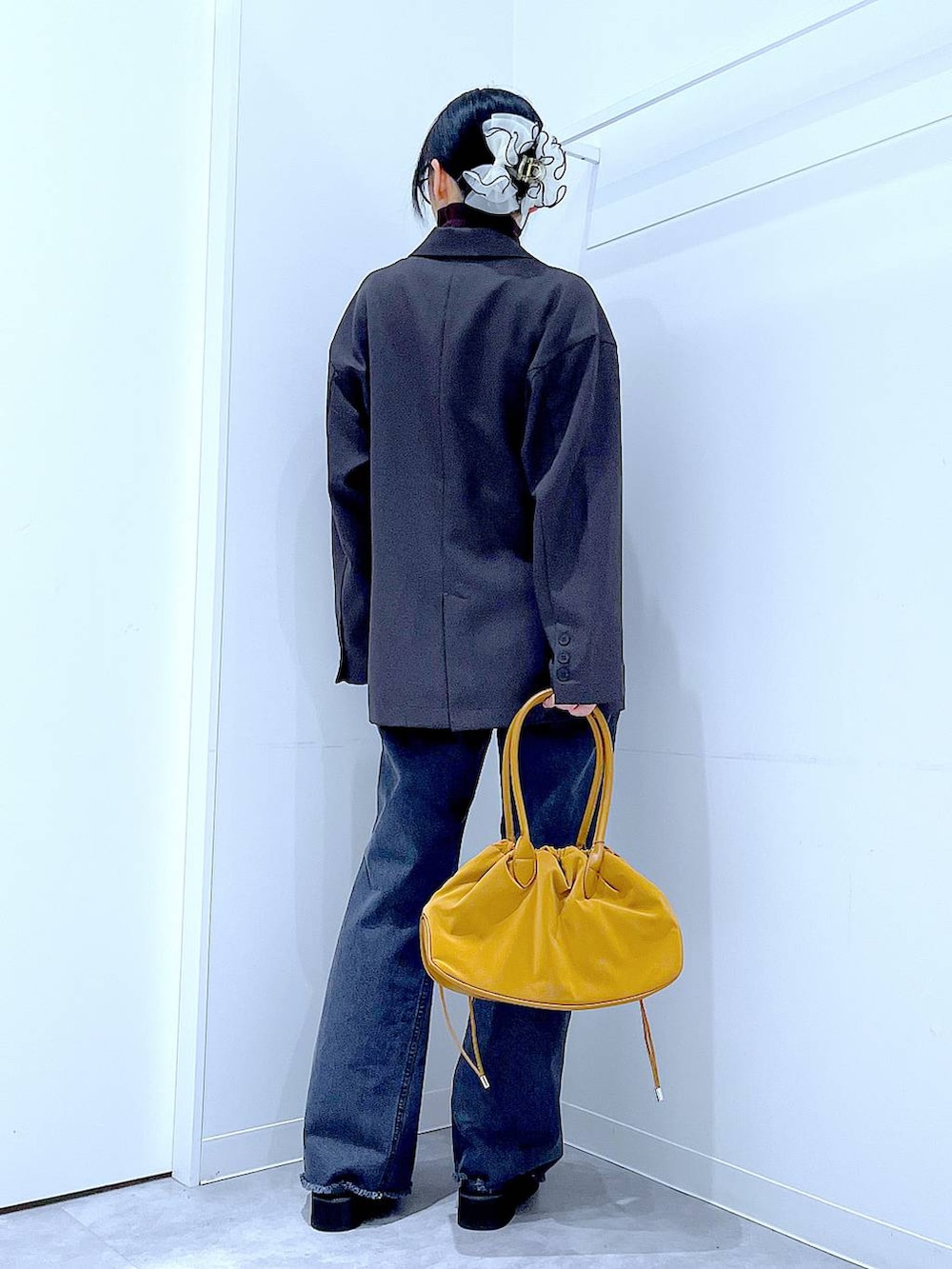 ブラウン系のハンドバッグ、ブラウン系のニット/セーター、グレー系のテーラードジャケットを着用したレディースの冬コーディネートの5枚目の写真