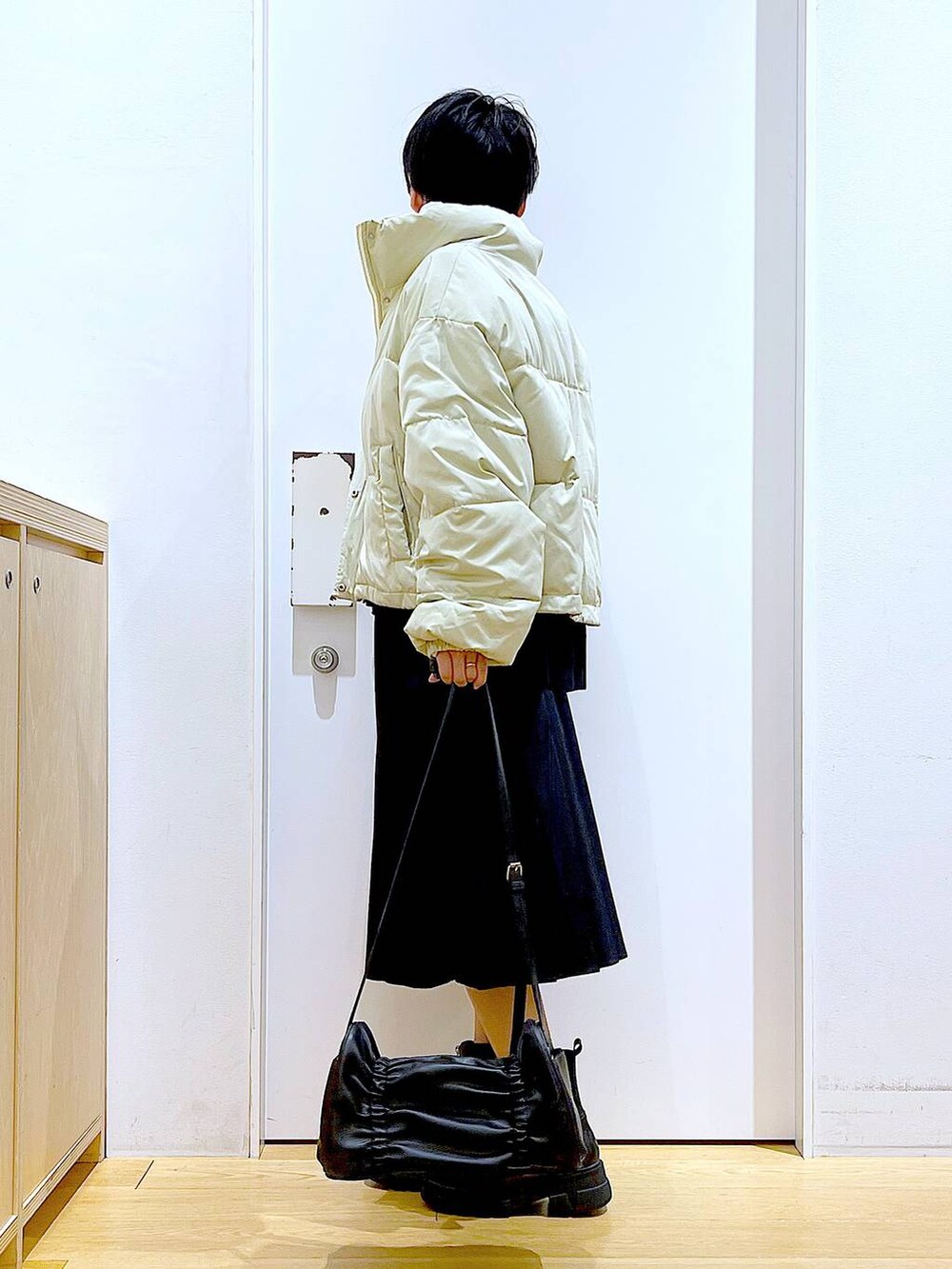 イエロー系のブルゾン、ブラック系のブーツ、ブラック系のスカートを着用したレディースの冬コーディネートの3枚目の写真