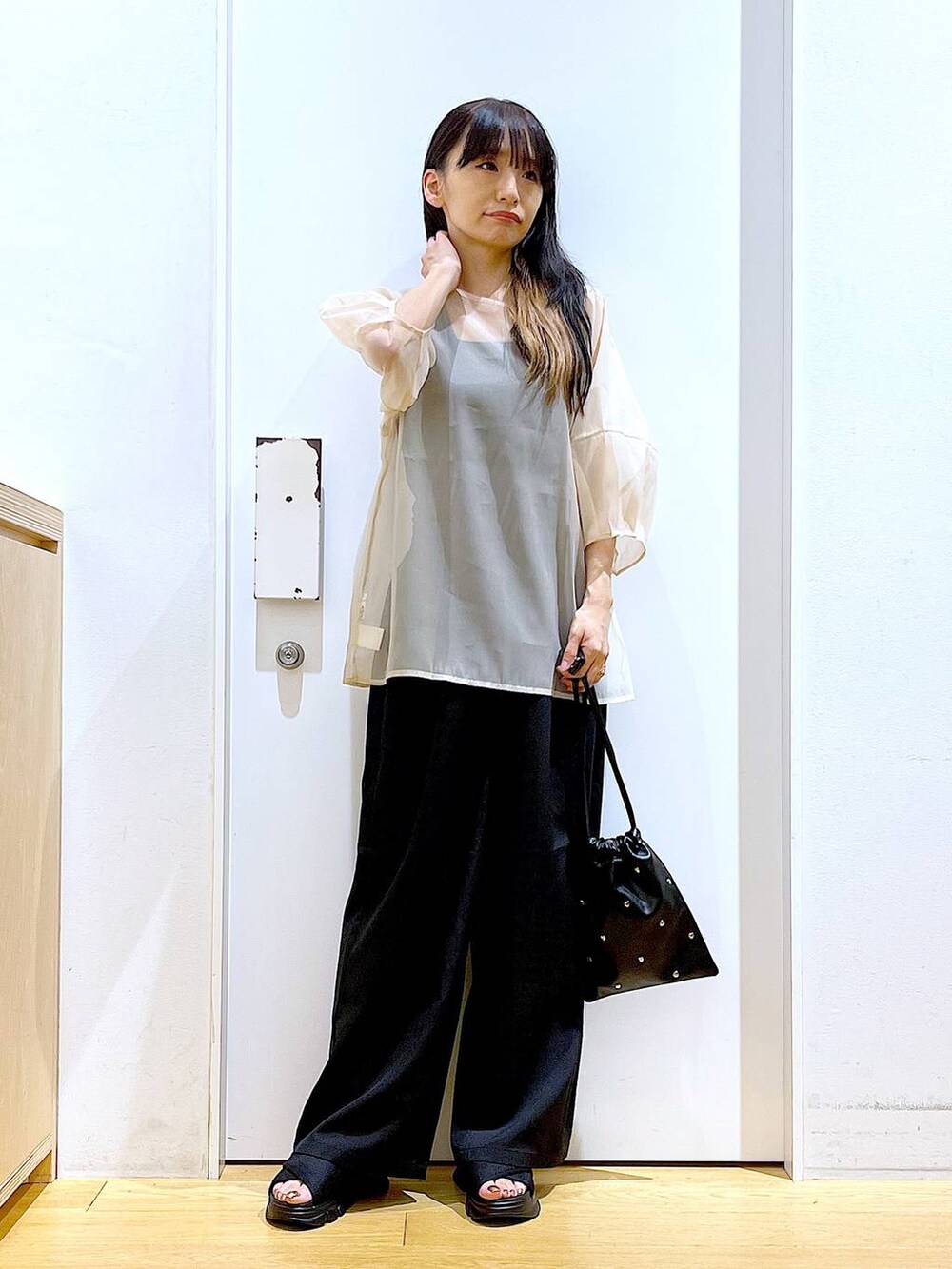 ブラック系のサンダル、ブラック系のニット/セーター、ブラック系のショルダーバッグを着用したレディースの夏コーディネートの2枚目の写真