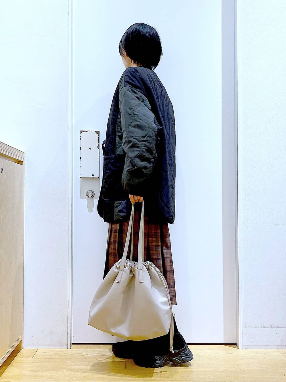 ベージュ系のトートバッグ、ブラック系のブルゾン、ブラック系のTシャツ/カットソーを着用したレディースの秋コーディネートの3枚目の写真