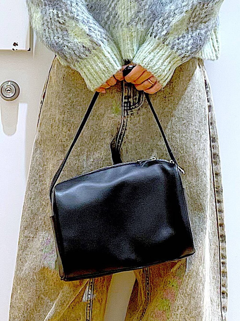 ブラック系のショルダーバッグ、ブラック系のブーツ、ベージュ系のデニムパンツを着用したレディースの冬コーディネートの9枚目の写真