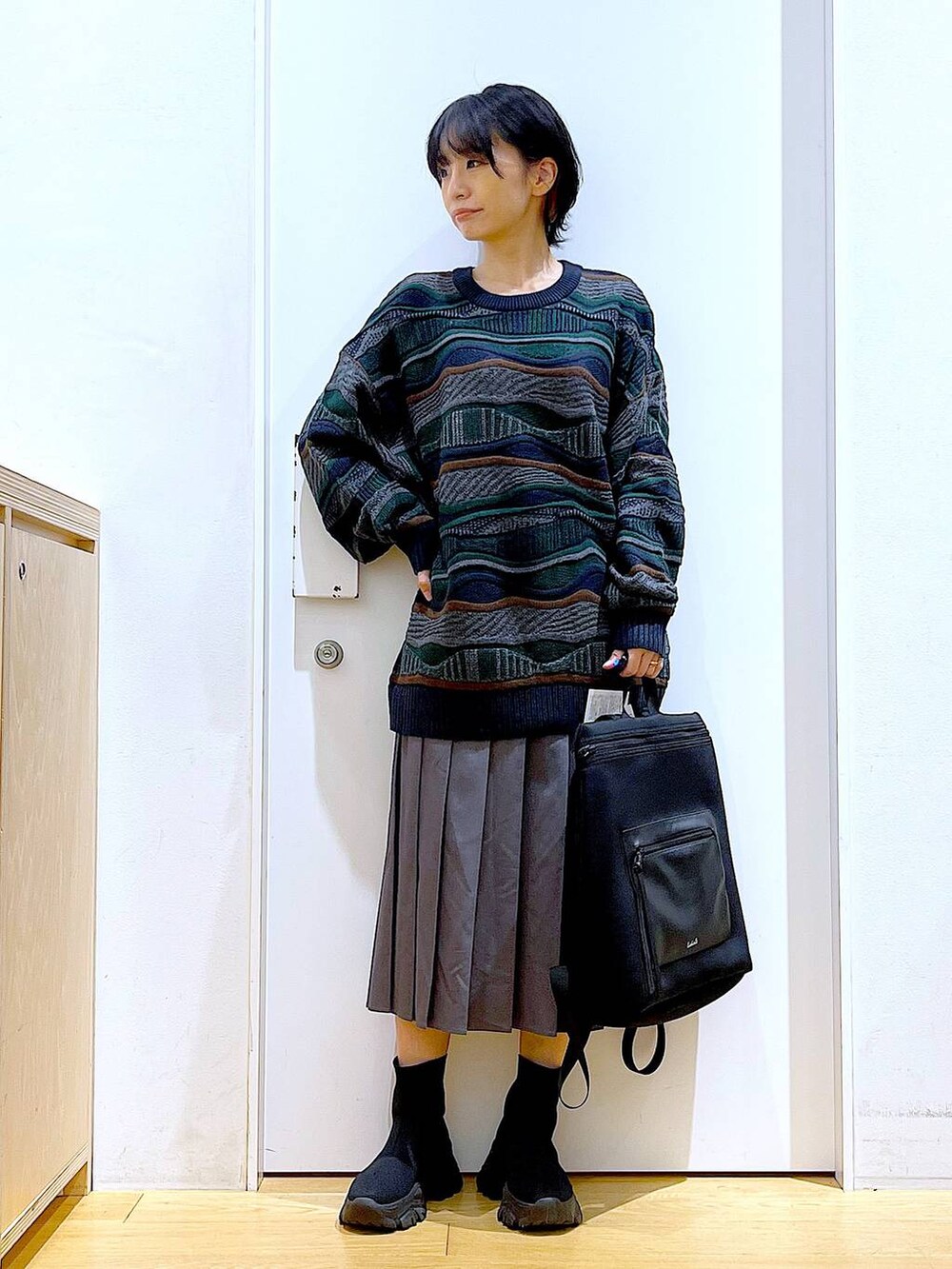 ブラック系のバックパック/リュック、ブラック系のブーツ、グレー系のスカートを着用したレディースの秋コーディネートの2枚目の写真