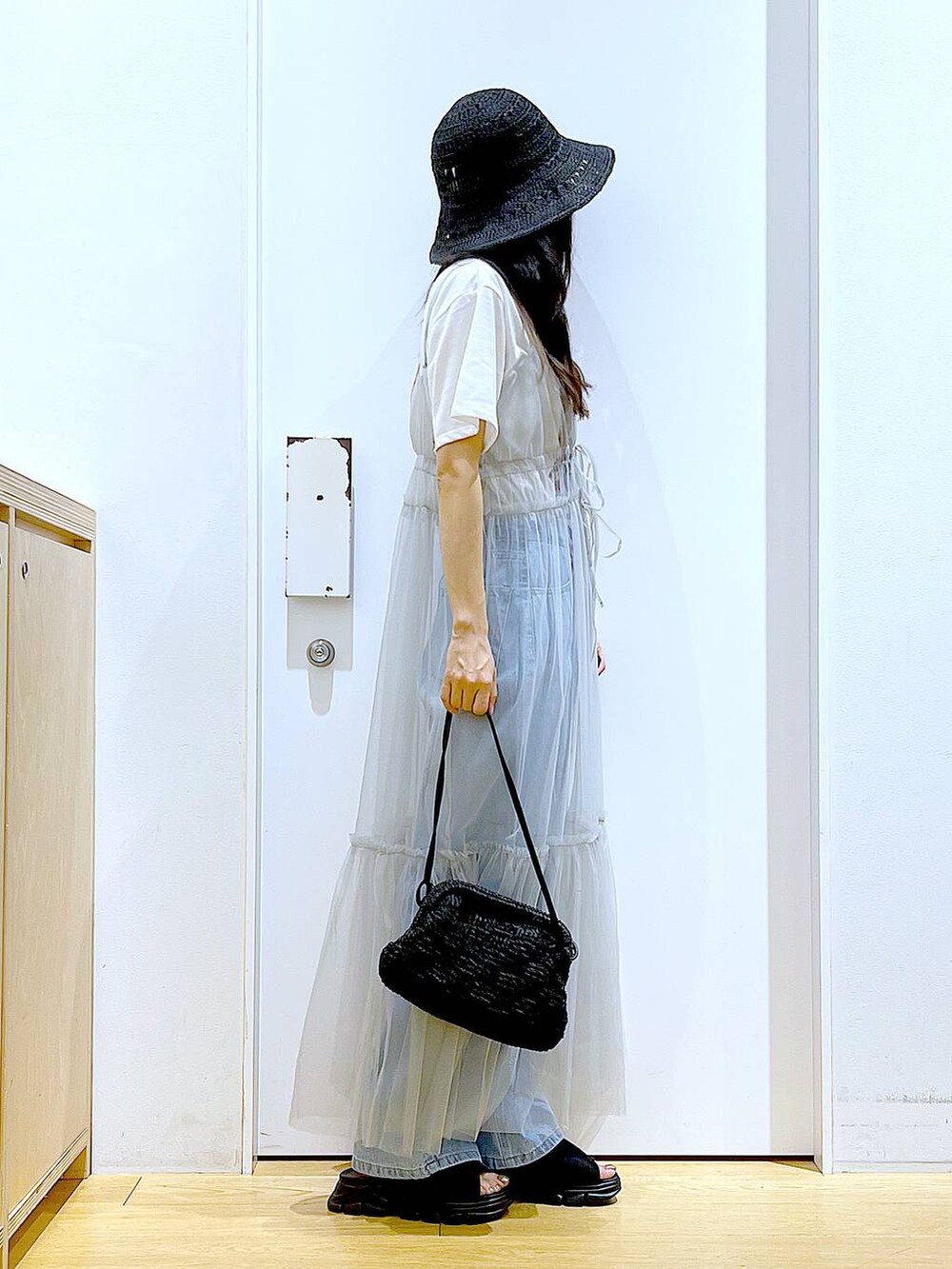グレー系のワンピース、ブルー系のデニムパンツ、ブラック系のショルダーバッグを着用したレディースの夏コーディネートの4枚目の写真