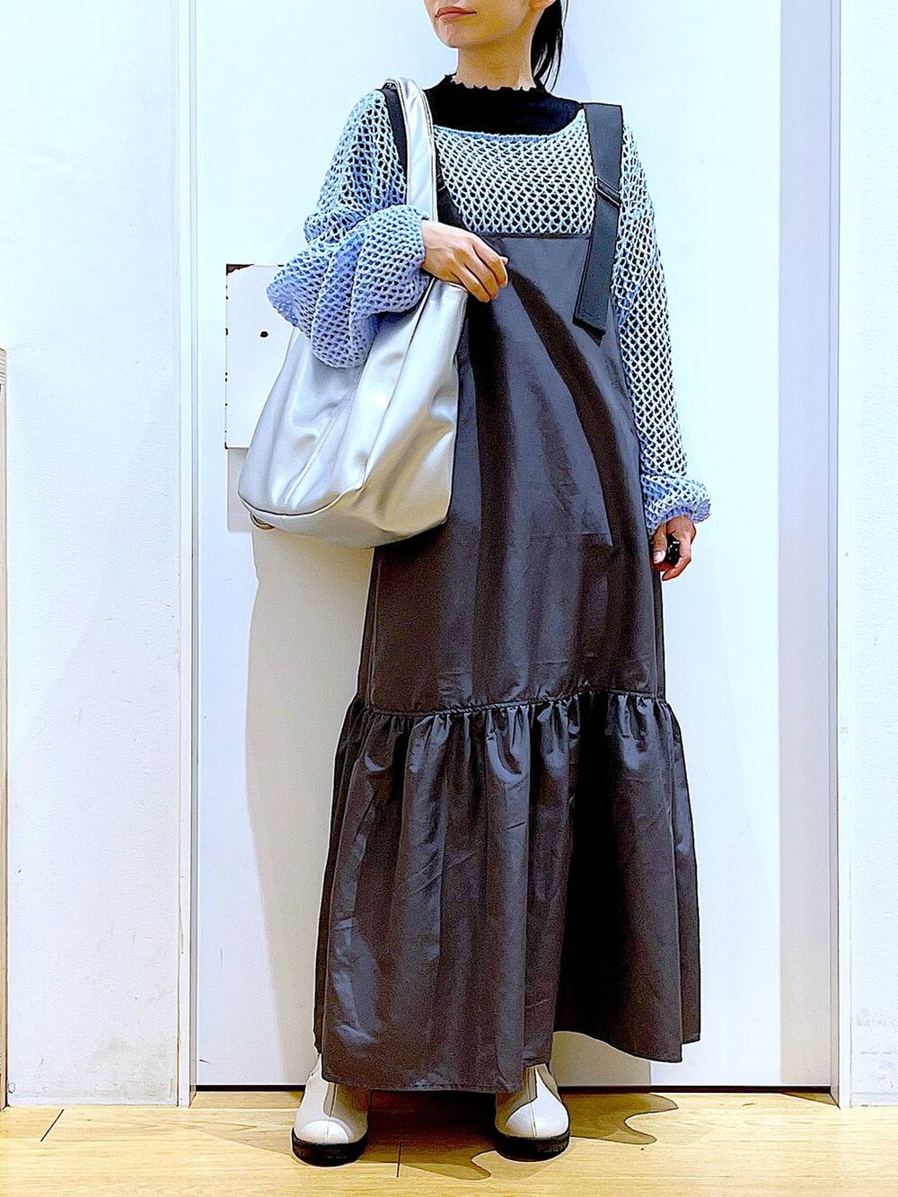 ブラック系のTシャツ/カットソー、ブルー系のニット/セーター、シルバー系のトートバッグを着用したレディースの春コーディネートの6枚目の写真