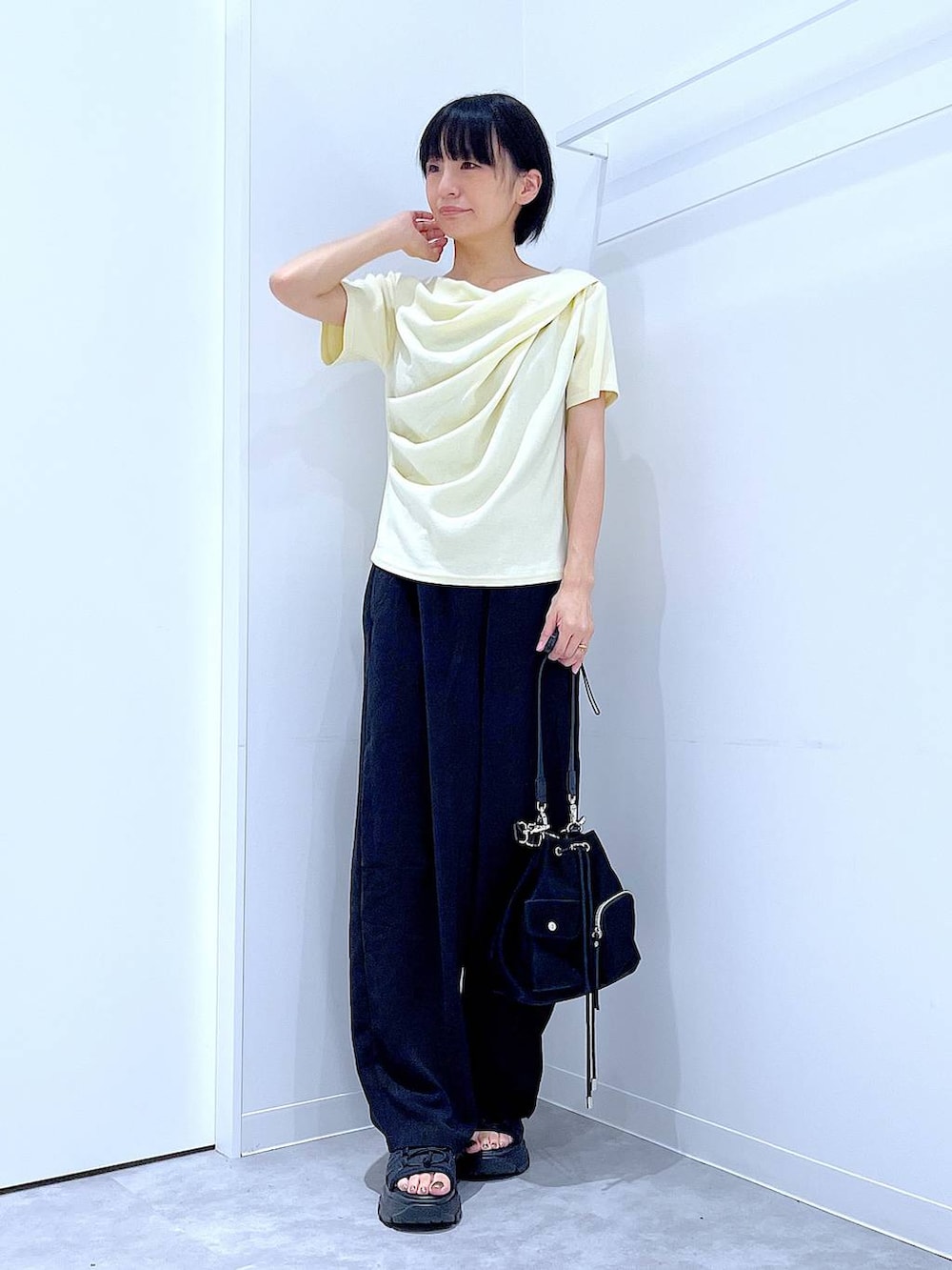 ブラック系のスニーカー、ブラック系のショルダーバッグ、イエロー系のTシャツ/カットソーを着用したレディースの夏コーディネートの2枚目の写真