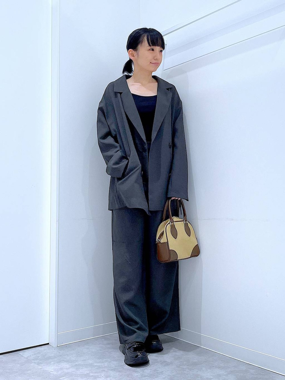 ブラック系のローファー、ベージュ系のハンドバッグ、グレー系のテーラードジャケットを着用したレディースの秋コーディネートの2枚目の写真