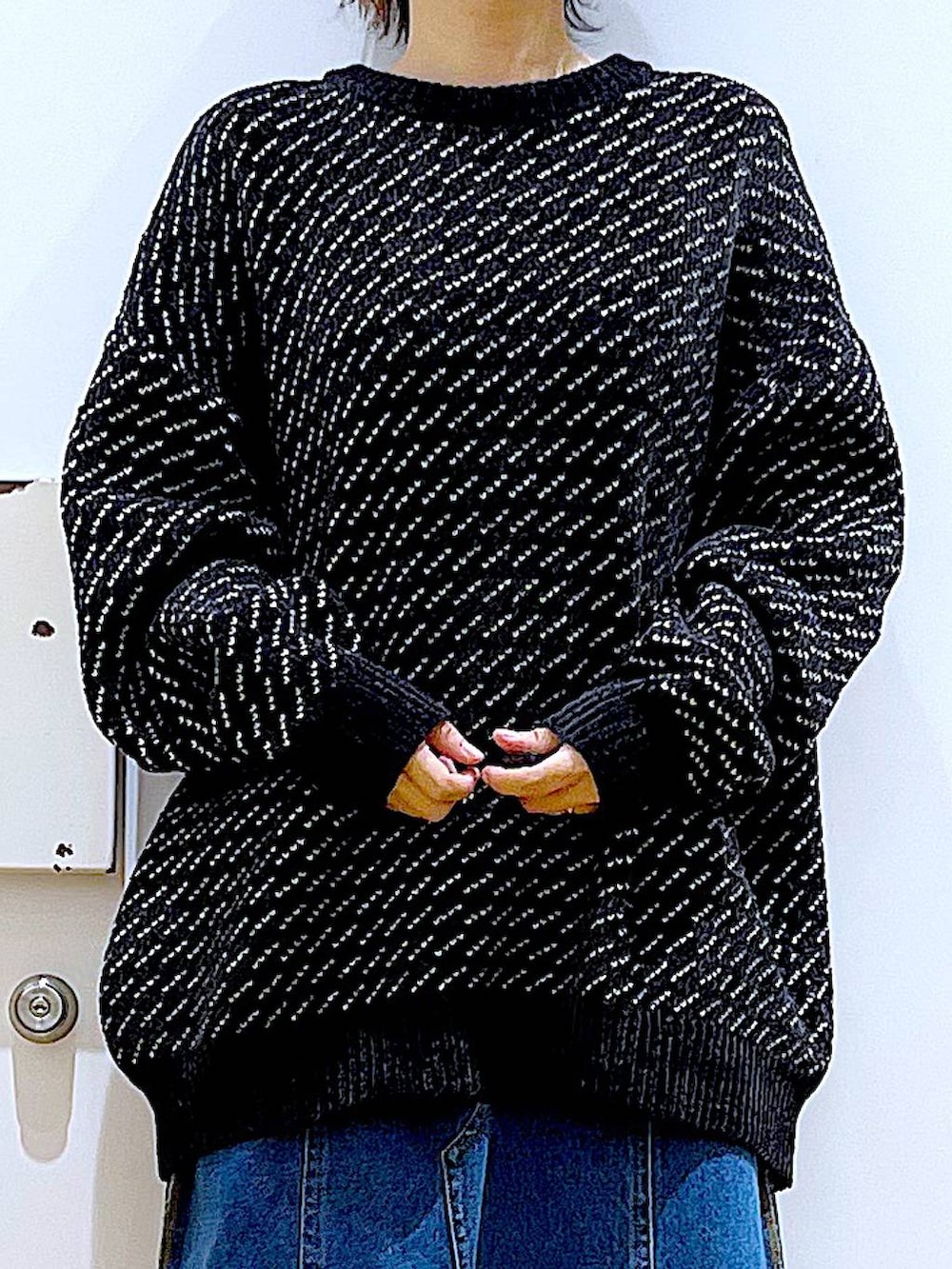 レッド系のショルダーバッグ、ブルー系のデニムスカート、ブラック系のニット/セーターを着用したレディースの冬コーディネートの7枚目の写真