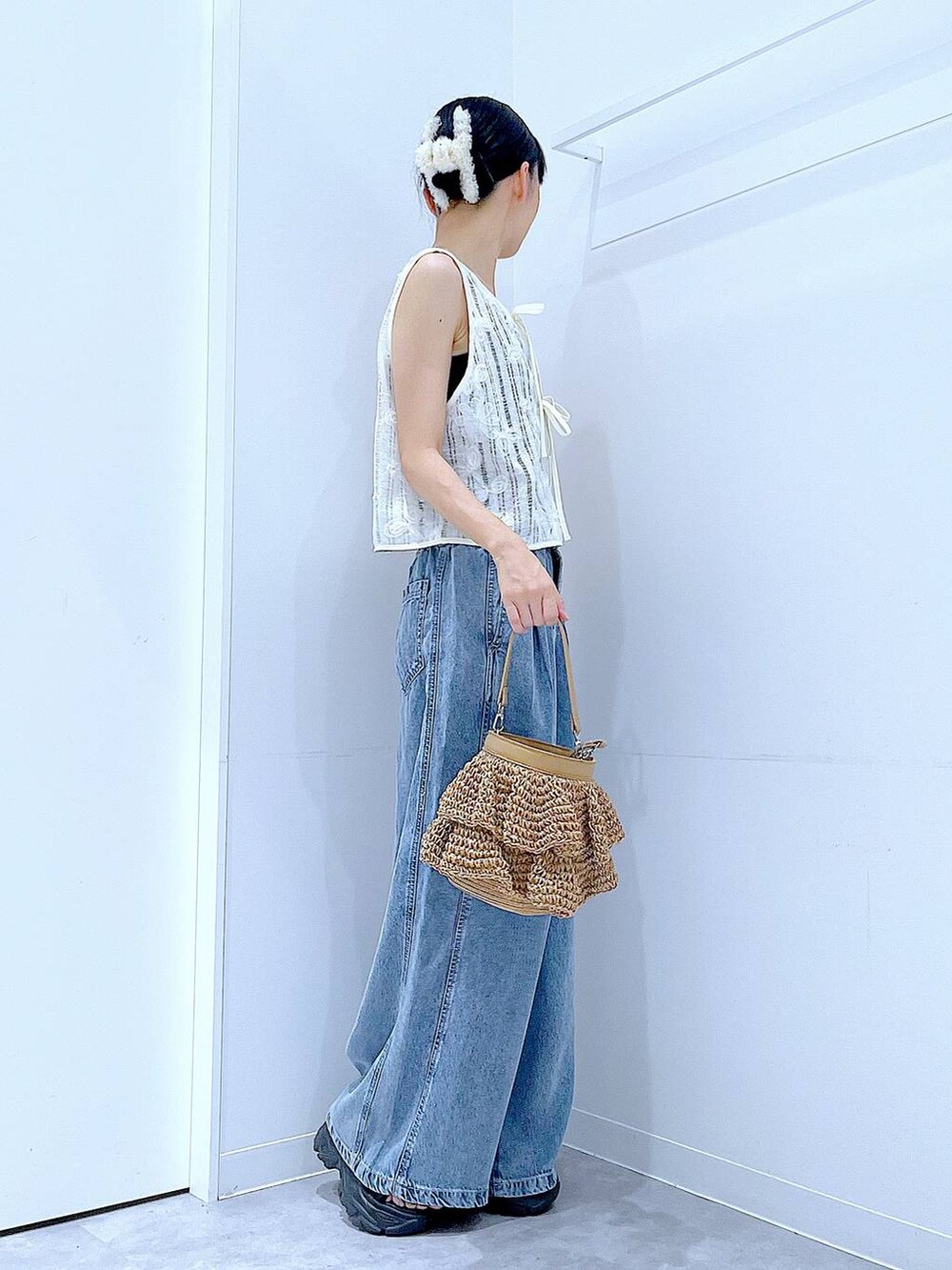 ベージュ系のショルダーバッグ、ブルー系のデニムパンツ、ベージュ系のベストを着用したレディースの夏コーディネートの4枚目の写真