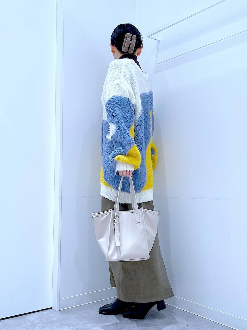 イエロー系のカーディガン/ボレロ、ブラック系のブーツ、グリーン系のスカートを着用したレディースの冬コーディネートの3枚目の写真