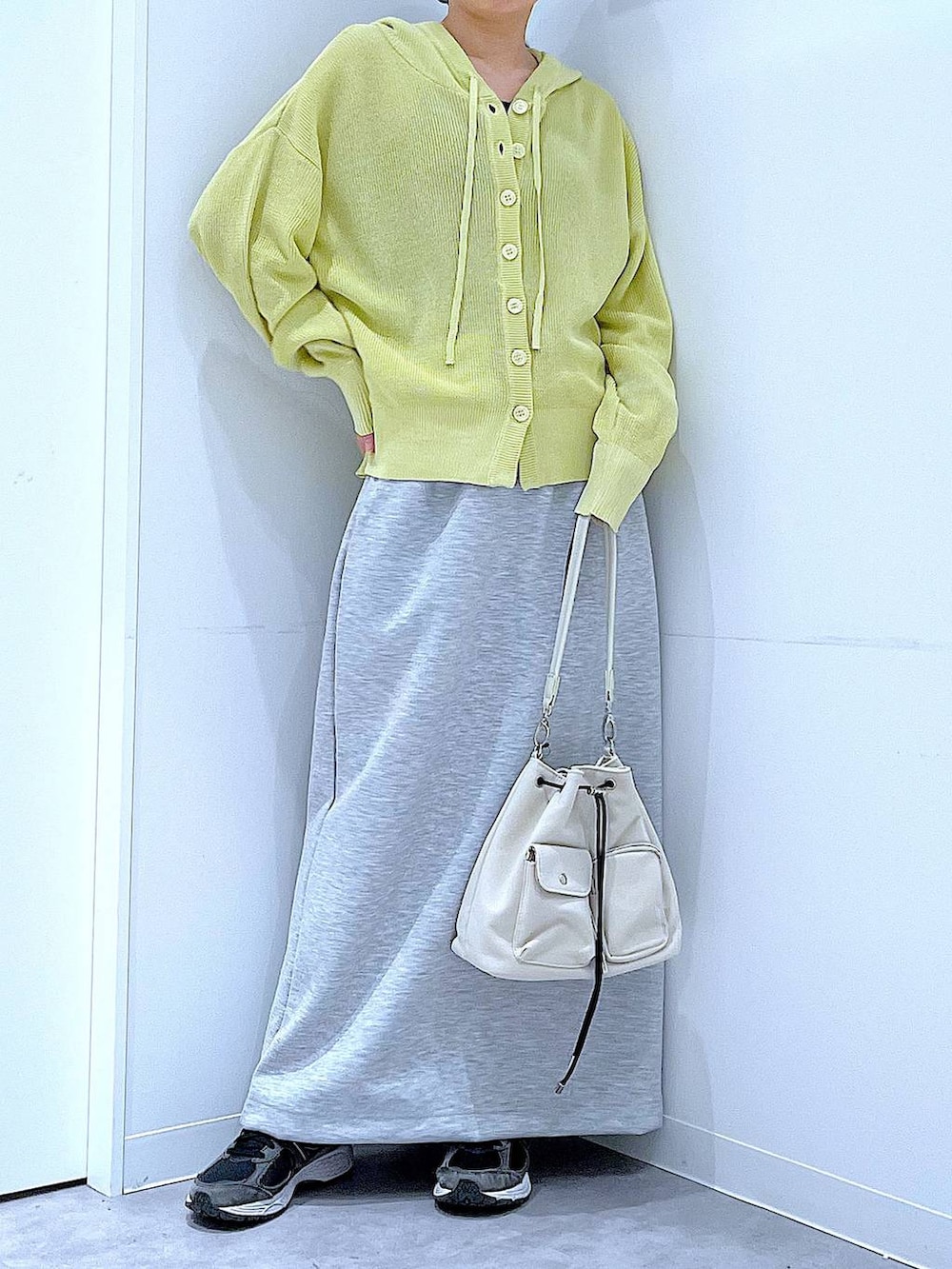 ベージュ系のショルダーバッグ、グレー系のスカート、イエロー系のカーディガン/ボレロを着用したレディースの春コーディネートの6枚目の写真