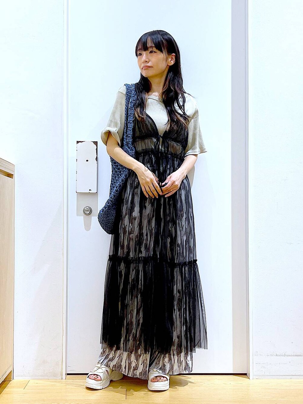 ブラック系のワンピース、ホワイト系のサンダル、ブルー系のトートバッグを着用したレディースの夏コーディネートの2枚目の写真