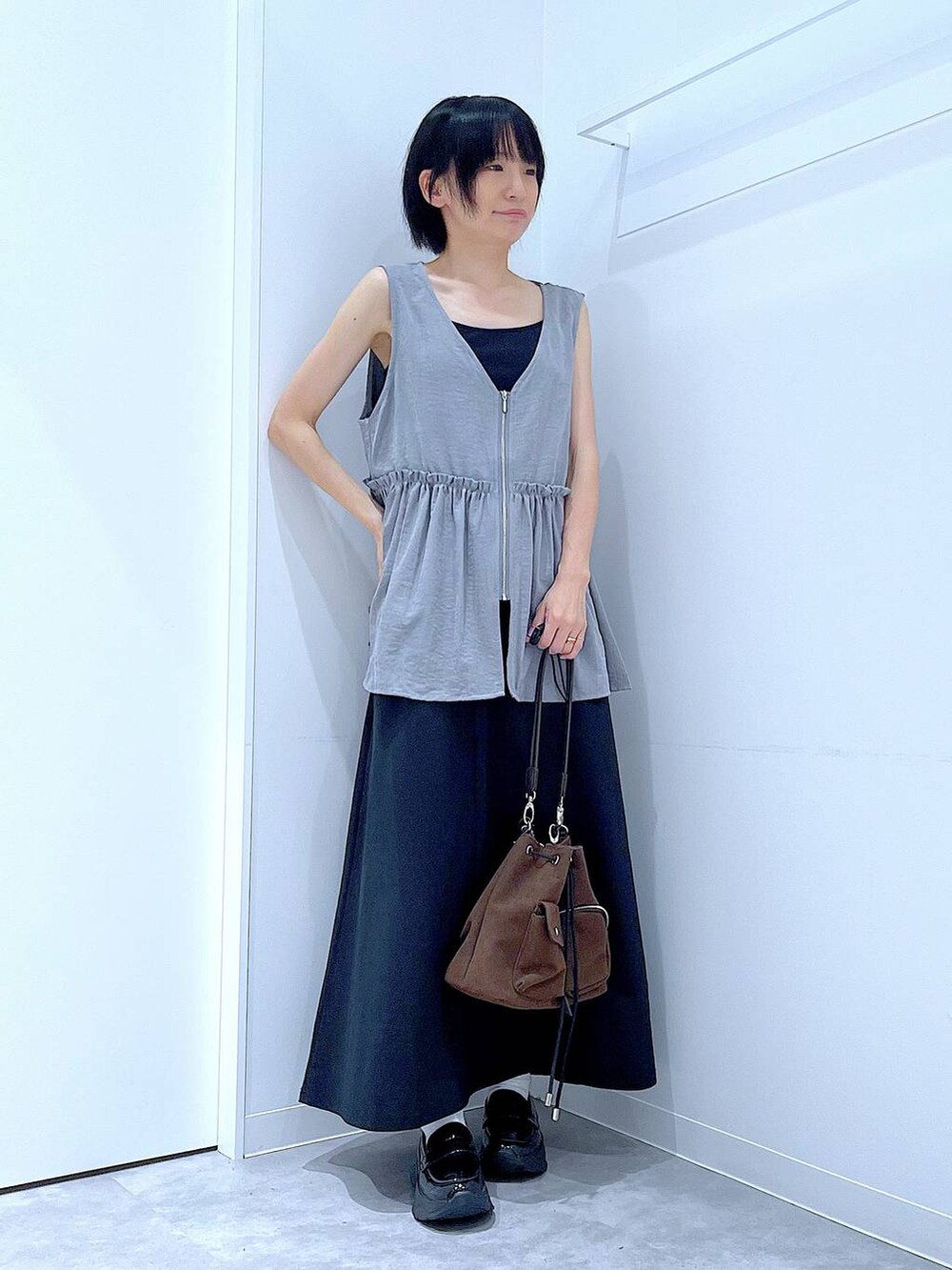 ブラック系のスカート、ブラック系のローファー、ブラウン系のショルダーバッグを着用したレディースの秋コーディネートの2枚目の写真