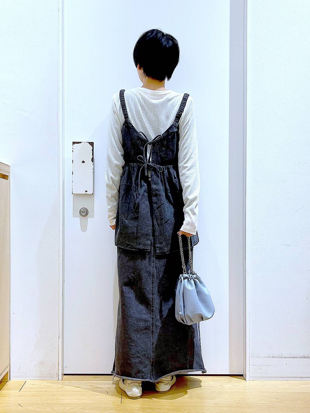 ブルー系のショルダーバッグ、ホワイト系のパンプス、ブラック系のデニムスカートを着用したレディースの春コーディネートの5枚目の写真