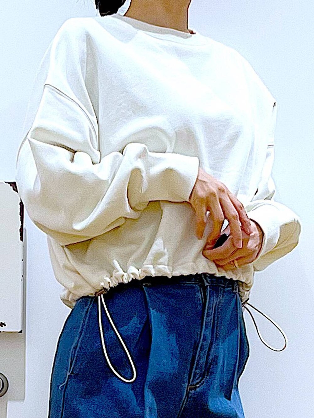 ホワイト系のスウェット、ブルー系のデニムパンツ、ベージュ系のスニーカーを着用したレディースの冬コーディネートの7枚目の写真