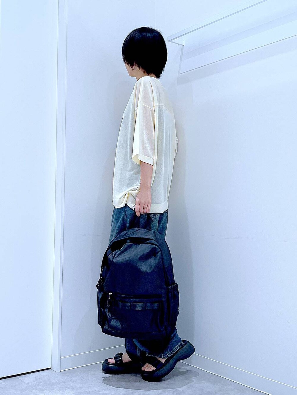 ブルー系のデニムパンツ、ブラック系のバックパック/リュック、ブラック系のサンダルを着用したレディースの夏コーディネートの3枚目の写真