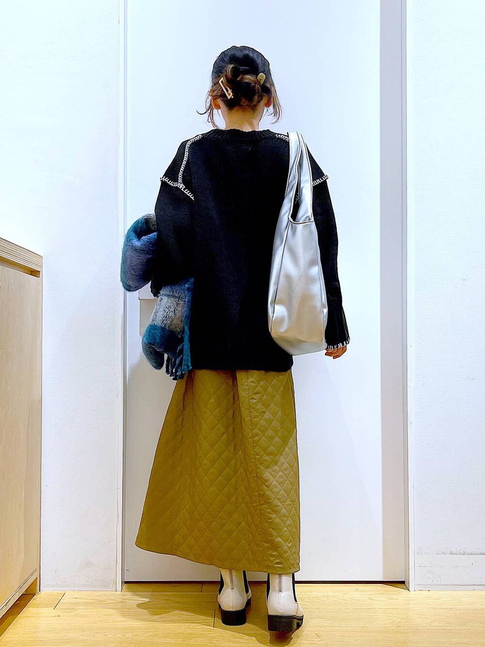 シルバー系のトートバッグ、ベージュ系のブーツ、ブラック系のニット/セーターを着用したレディースの冬コーディネートの5枚目の写真