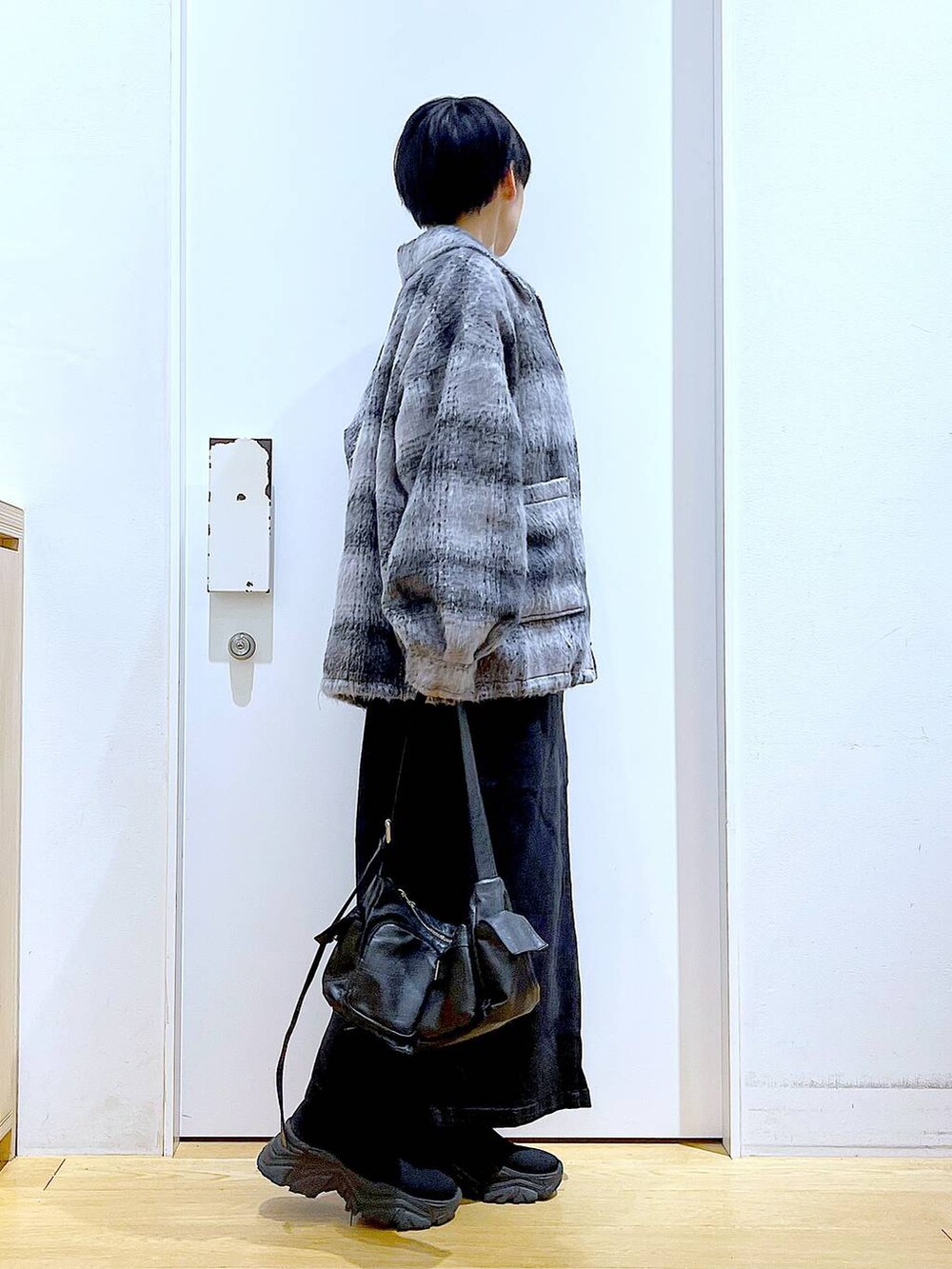 グレー系のジャンパースカート、ブラック系のブーツ、ブラック系のショルダーバッグを着用したレディースの冬コーディネートの4枚目の写真