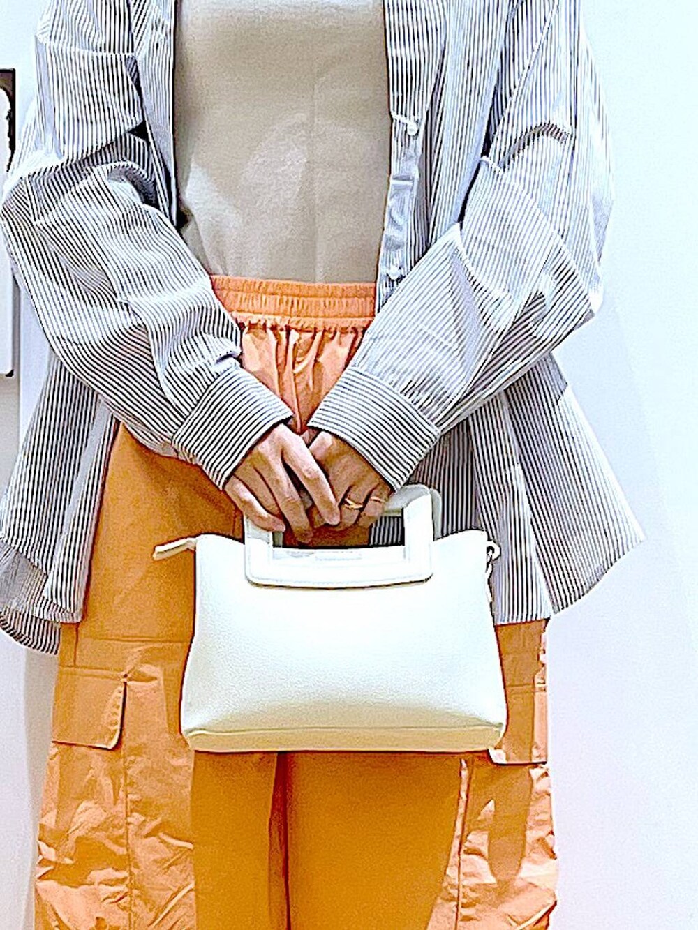 ホワイト系のシャツ/ブラウス、イエロー系のニット/セーター、ホワイト系のショルダーバッグを着用したレディースの春コーディネートの9枚目の写真