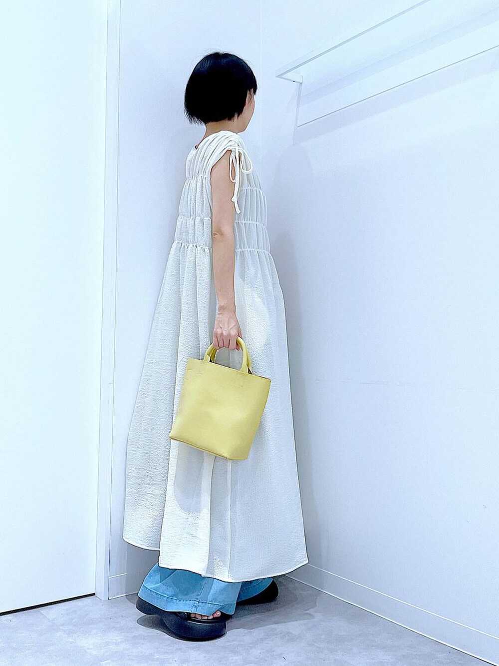 ブラック系のサンダル、ブルー系のデニムパンツ、ベージュ系のワンピースを着用したレディースの夏コーディネートの4枚目の写真