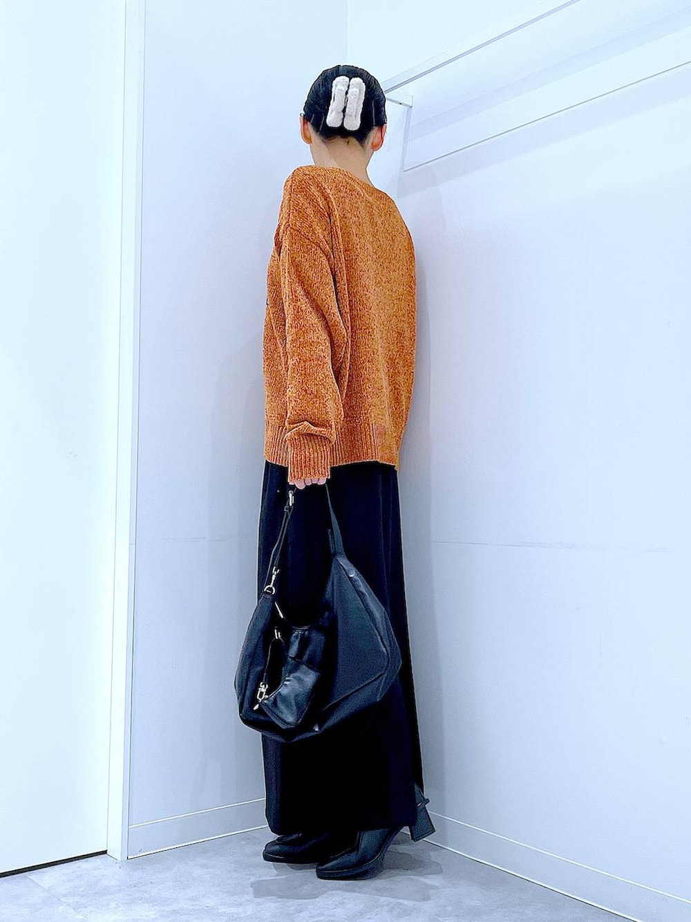 ブラック系のスカート、ブラック系のブーツ、ブラック系のショルダーバッグを着用したレディースの冬コーディネートの3枚目の写真