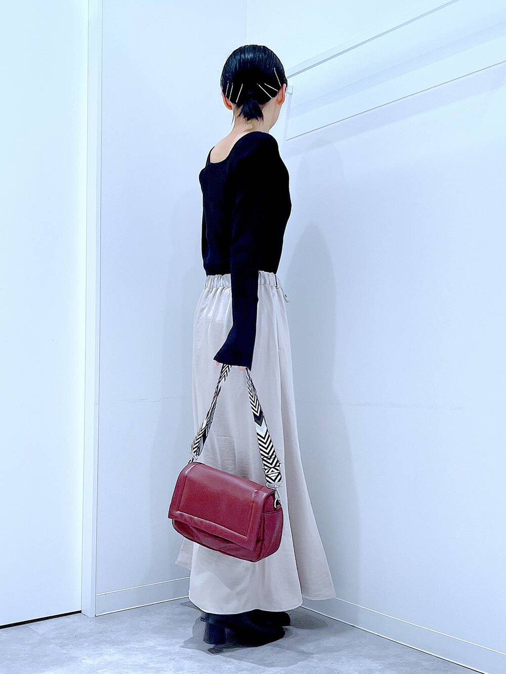 ブラック系のニット/セーター、ベージュ系のスカート、レッド系のショルダーバッグを着用したレディースの秋コーディネートの4枚目の写真