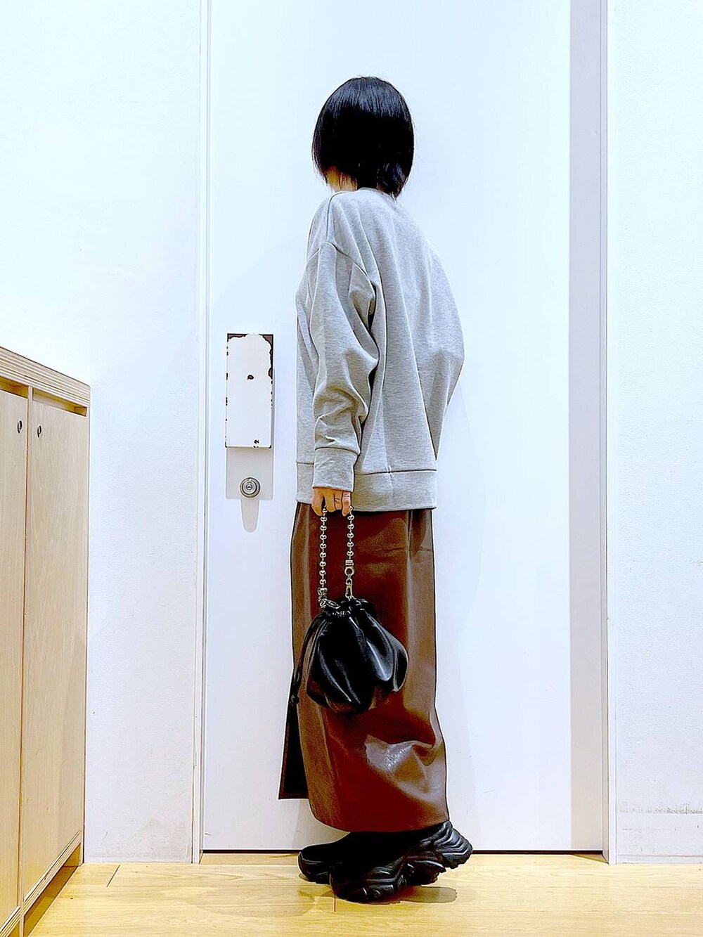 ブラウン系のスカート、ブラック系のショルダーバッグ、ブラック系のブーツを着用したレディースの冬コーディネートの3枚目の写真