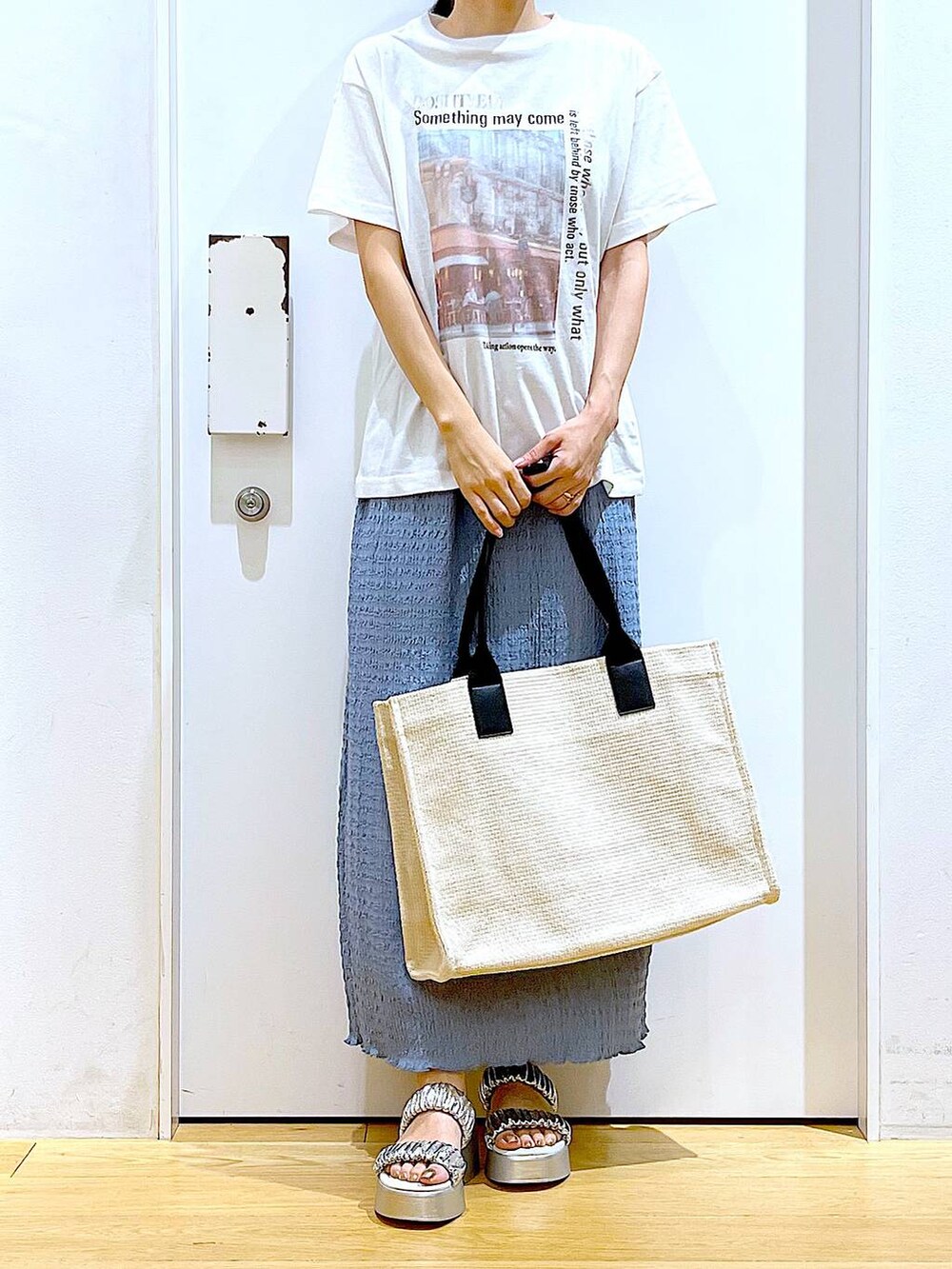 シルバー系のサンダル、ブルー系のスカート、ホワイト系のトートバッグを着用したレディースの夏コーディネートの6枚目の写真