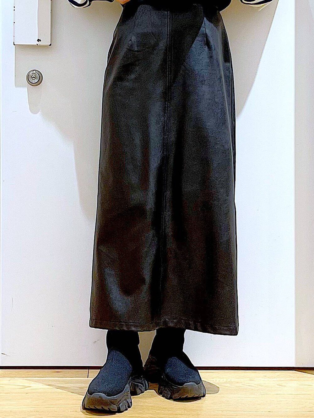 ブラック系のブーツ、ブラック系のスカート、シルバー系のショルダーバッグを着用したレディースの冬コーディネートの8枚目の写真