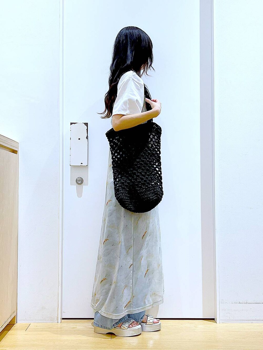 ブルー系のデニムパンツ、ブラック系のトートバッグ、ホワイト系のTシャツ/カットソーを着用したレディースの夏コーディネートの4枚目の写真