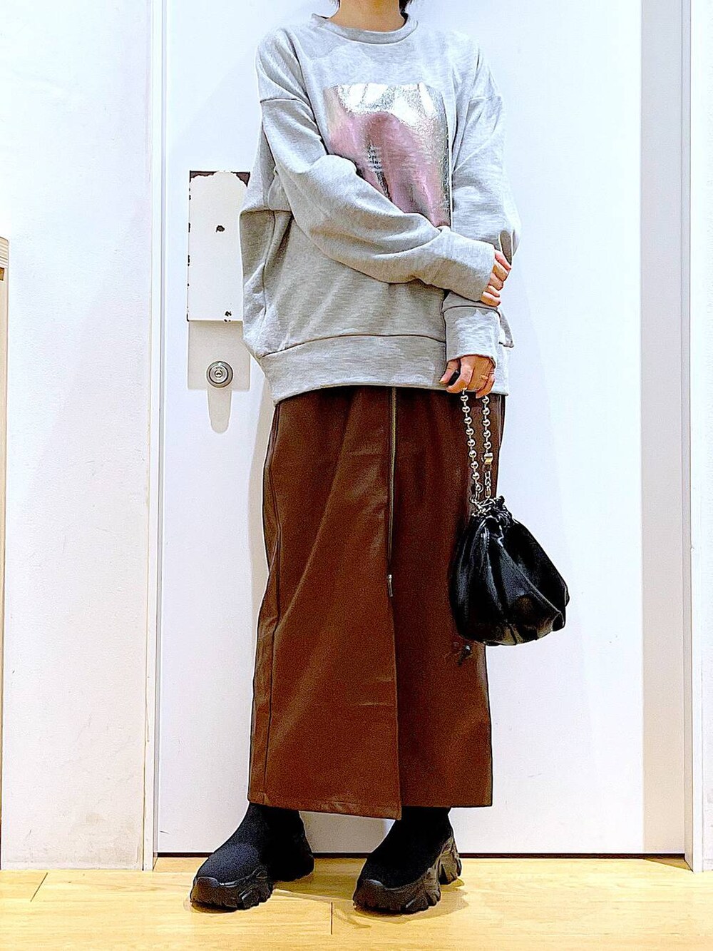 ブラウン系のスカート、ブラック系のショルダーバッグ、ブラック系のブーツを着用したレディースの冬コーディネートの6枚目の写真