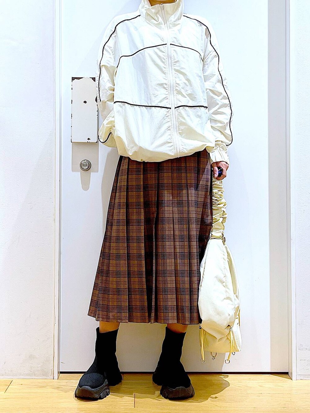 ホワイト系のショルダーバッグ、ベージュ系のブルゾン、ブラック系のブーツを着用したレディースの秋コーディネートの6枚目の写真