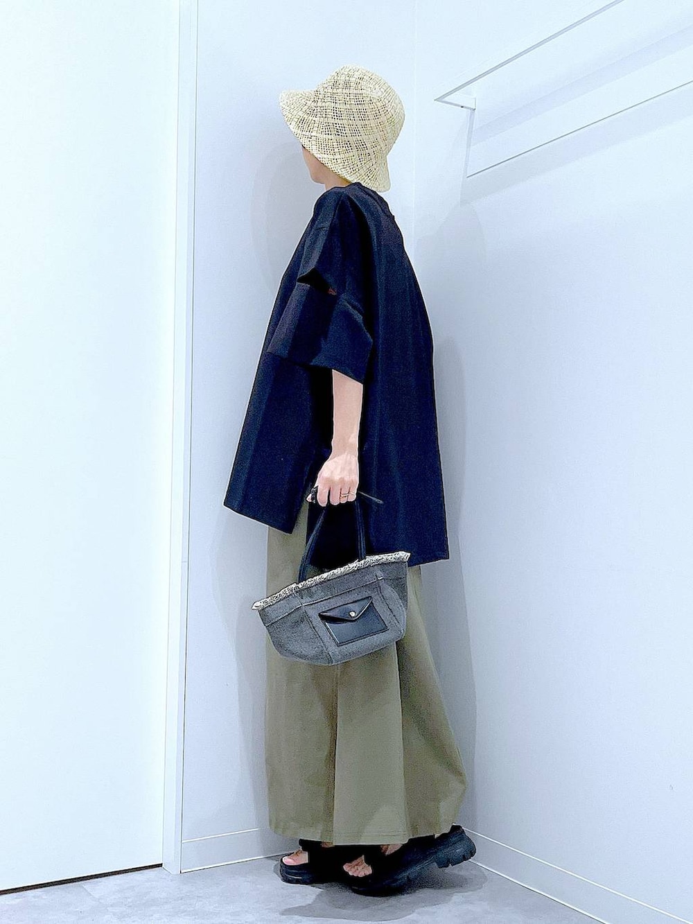 ブラック系のショルダーバッグ、ブラック系のサンダル、グリーン系のスカートを着用したレディースの夏コーディネートの3枚目の写真