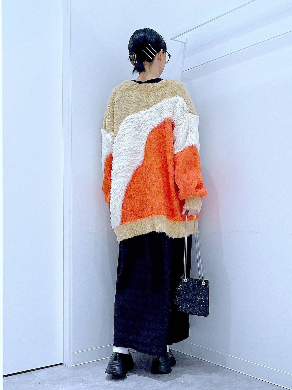 ブラック系のショルダーバッグ、ブラック系のローファー、オレンジ系のカーディガン/ボレロを着用したレディースの秋コーディネートの5枚目の写真