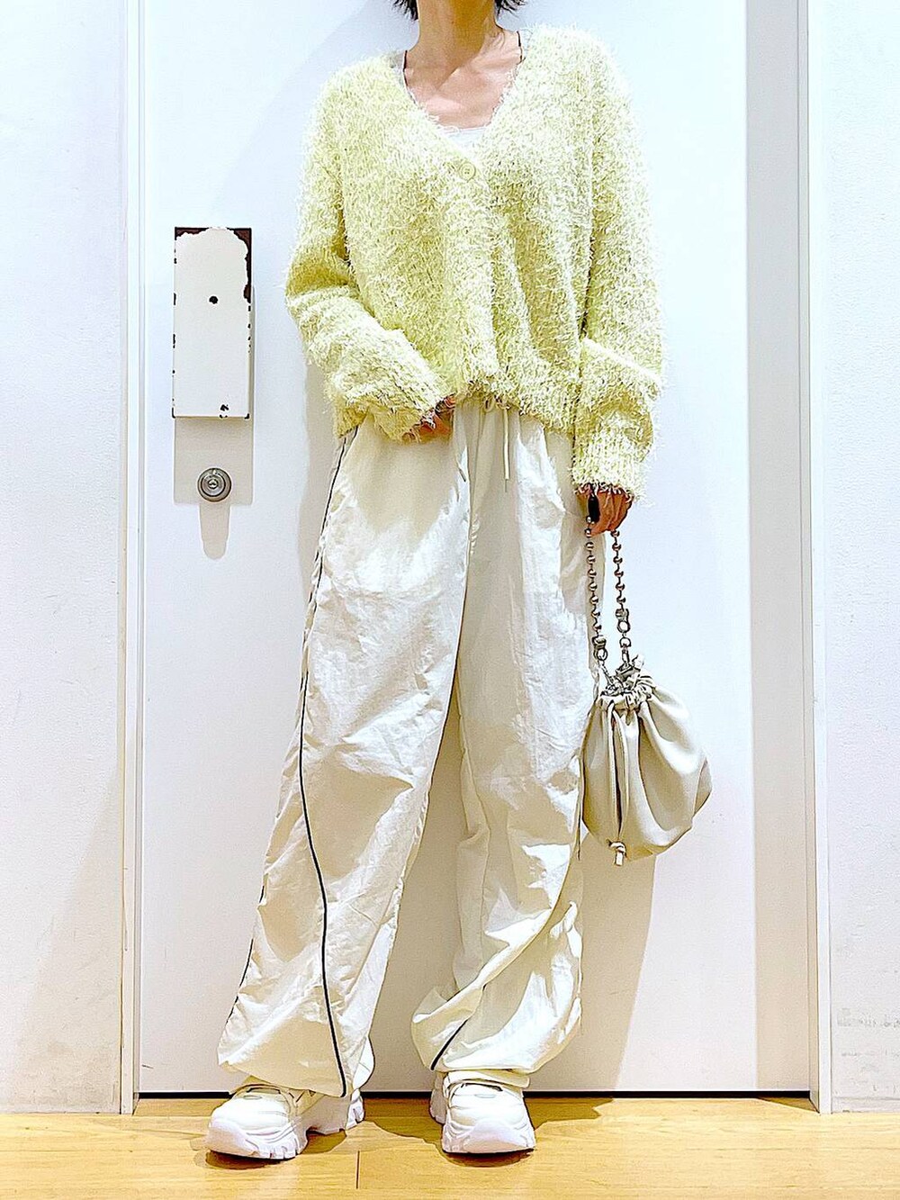 ベージュ系のショルダーバッグ、ホワイト系のスニーカー、イエロー系のカーディガン/ボレロを着用したレディースの秋コーディネートの6枚目の写真