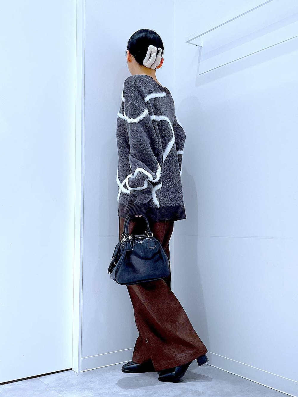 ブラック系のブーツ、ブラウン系のスラックス、ブラック系のショルダーバッグを着用したレディースの冬コーディネートの3枚目の写真