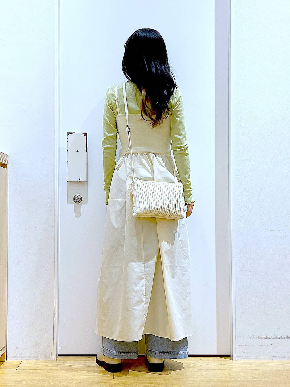 ホワイト系のショルダーバッグ、ベージュ系のブーツ、ブルー系のデニムパンツを着用したレディースの冬コーディネートの5枚目の写真