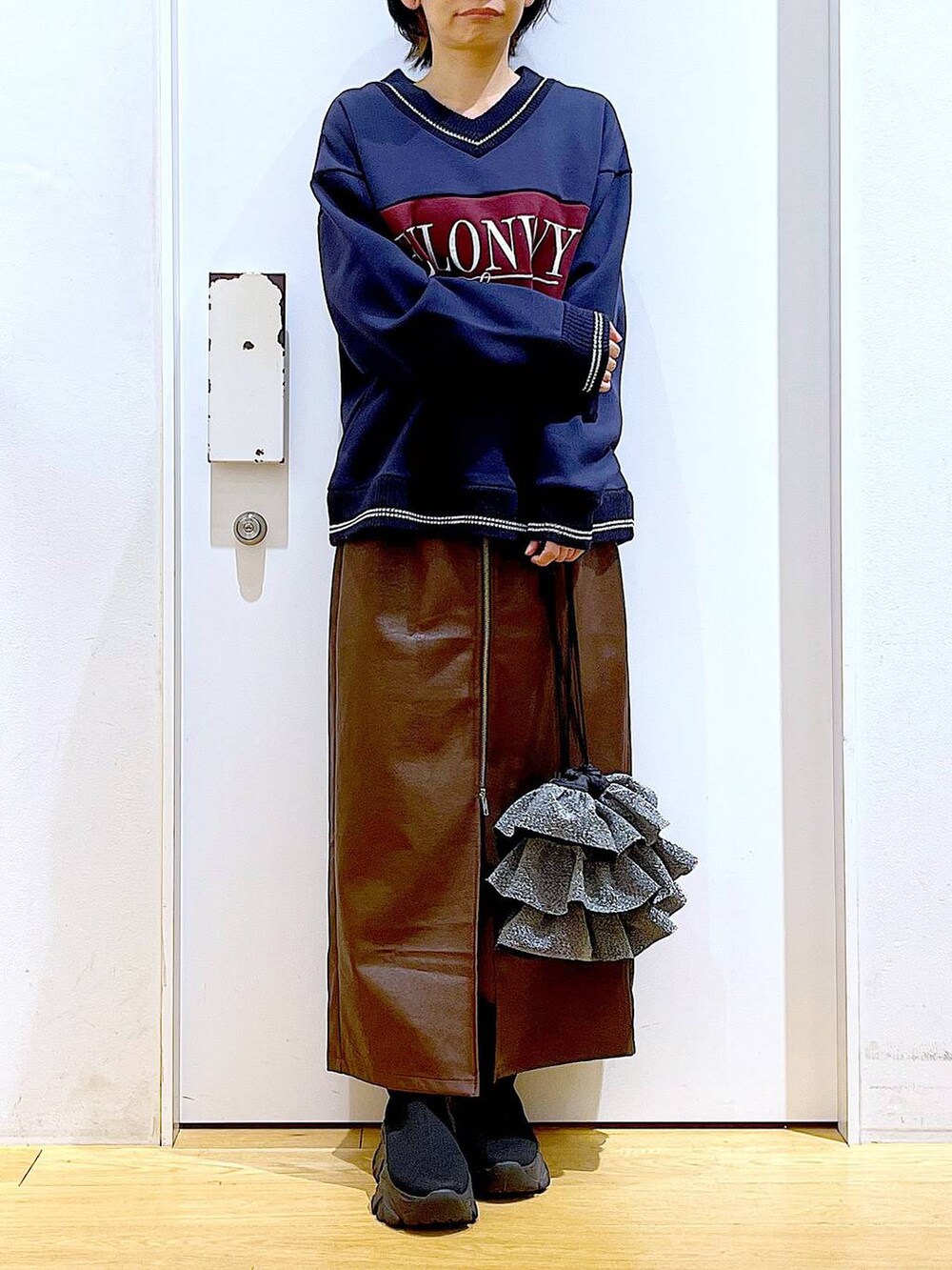 ブラウン系のスカート、ブラック系のブーツ、シルバー系のショルダーバッグを着用したレディースの冬コーディネートの6枚目の写真