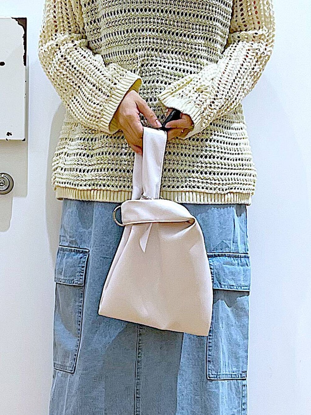 ブルー系のデニムスカート、ホワイト系のショルダーバッグ、ベージュ系のスニーカーを着用したレディースの春コーディネートの9枚目の写真