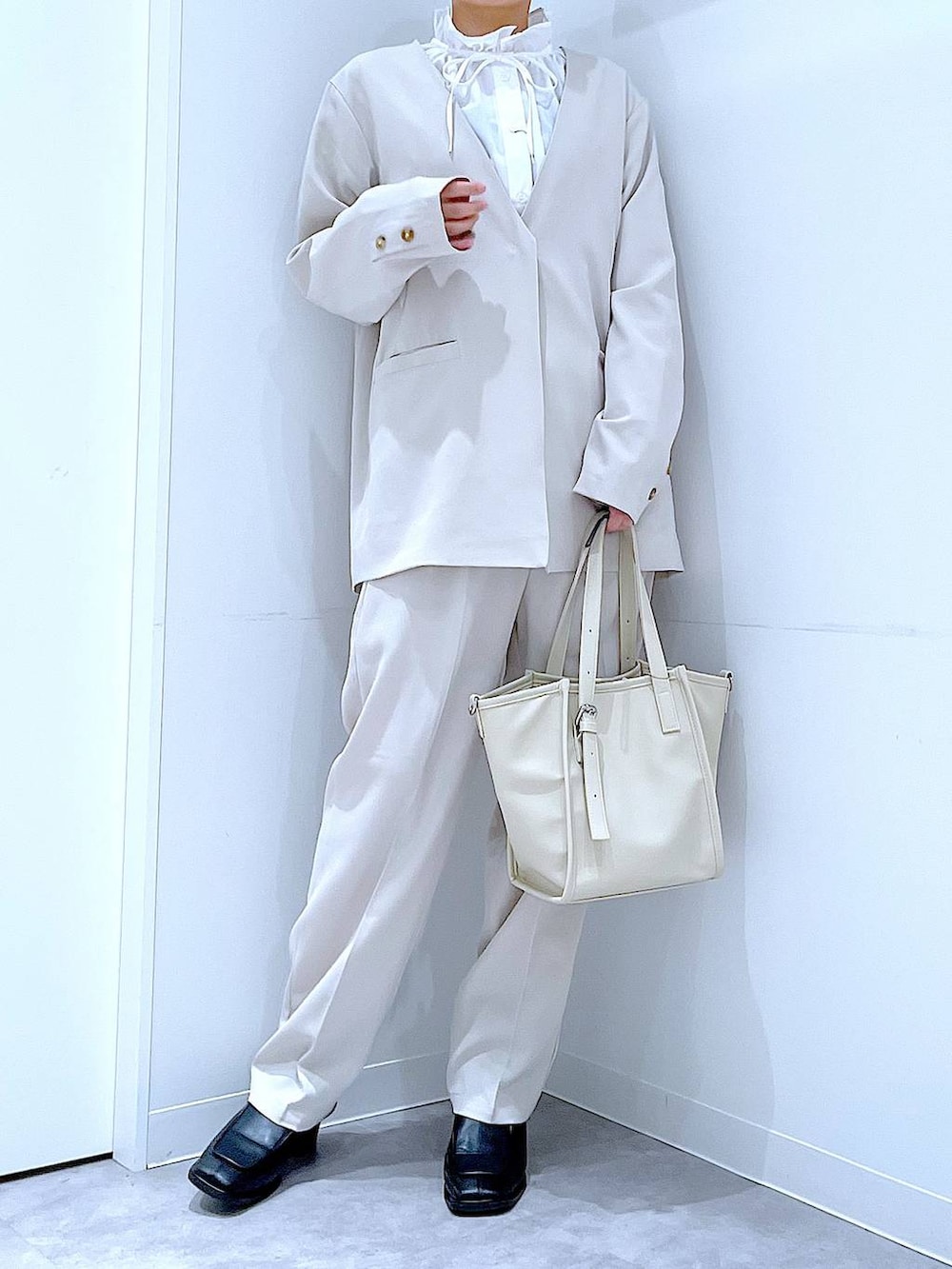 ブラック系のブーツ、ホワイト系のトートバッグ、ベージュ系のノーカラージャケットを着用したレディースの冬コーディネートの6枚目の写真