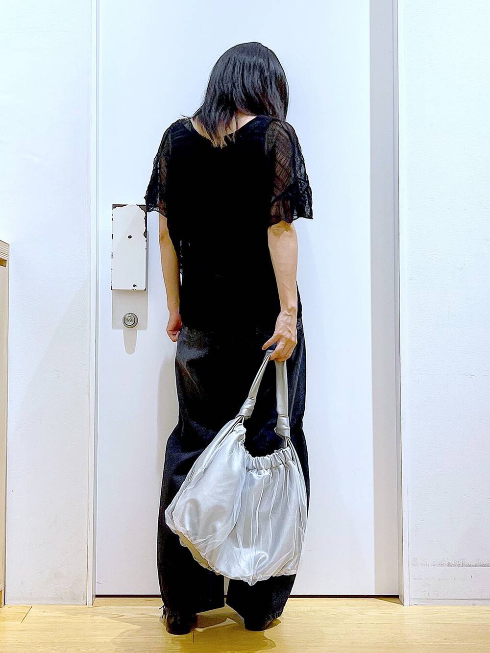 シルバー系のトートバッグ、ブラック系のデニムパンツ、ブラック系のカーディガン/ボレロを着用したレディースの秋コーディネートの5枚目の写真