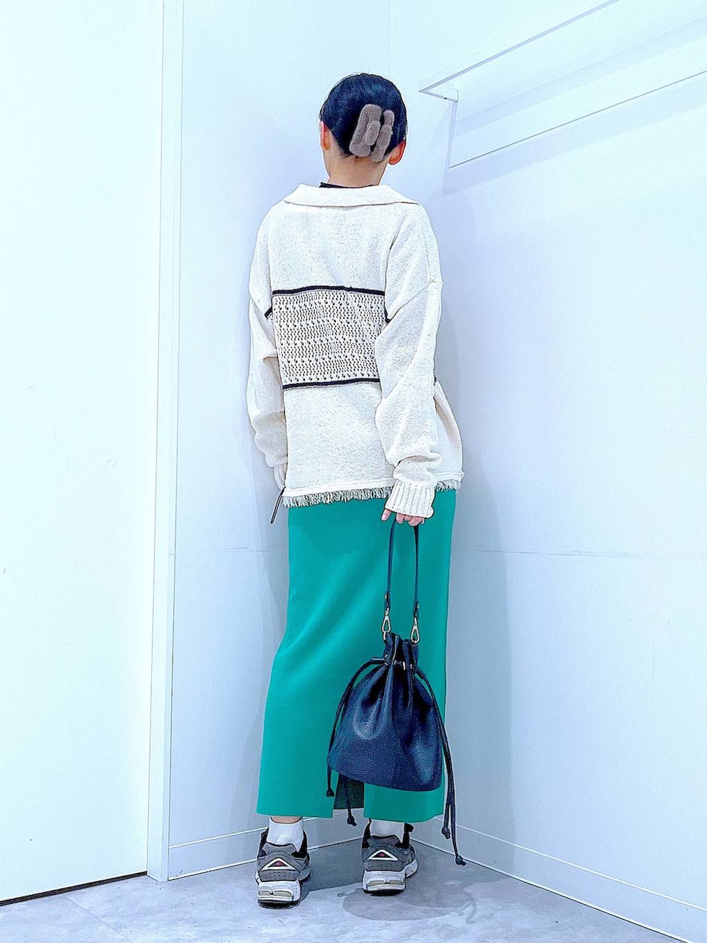 ブラック系のTシャツ/カットソー、グリーン系のスカート、ホワイト系のニット/セーターを着用したレディースの冬コーディネートの5枚目の写真