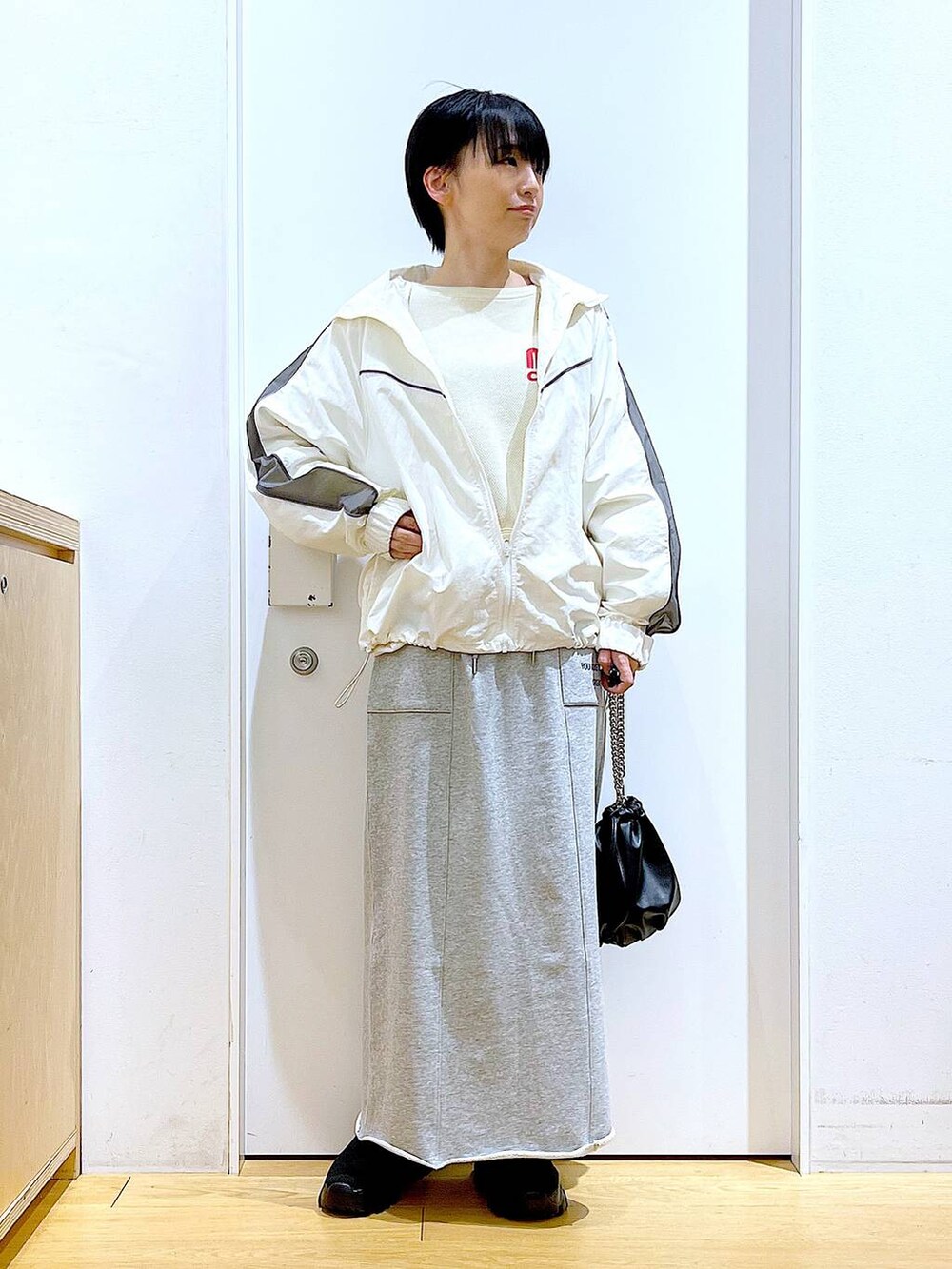 ブラック系のブーツ、ブラック系のショルダーバッグ、グレー系のスカートを着用したレディースの春コーディネートの2枚目の写真