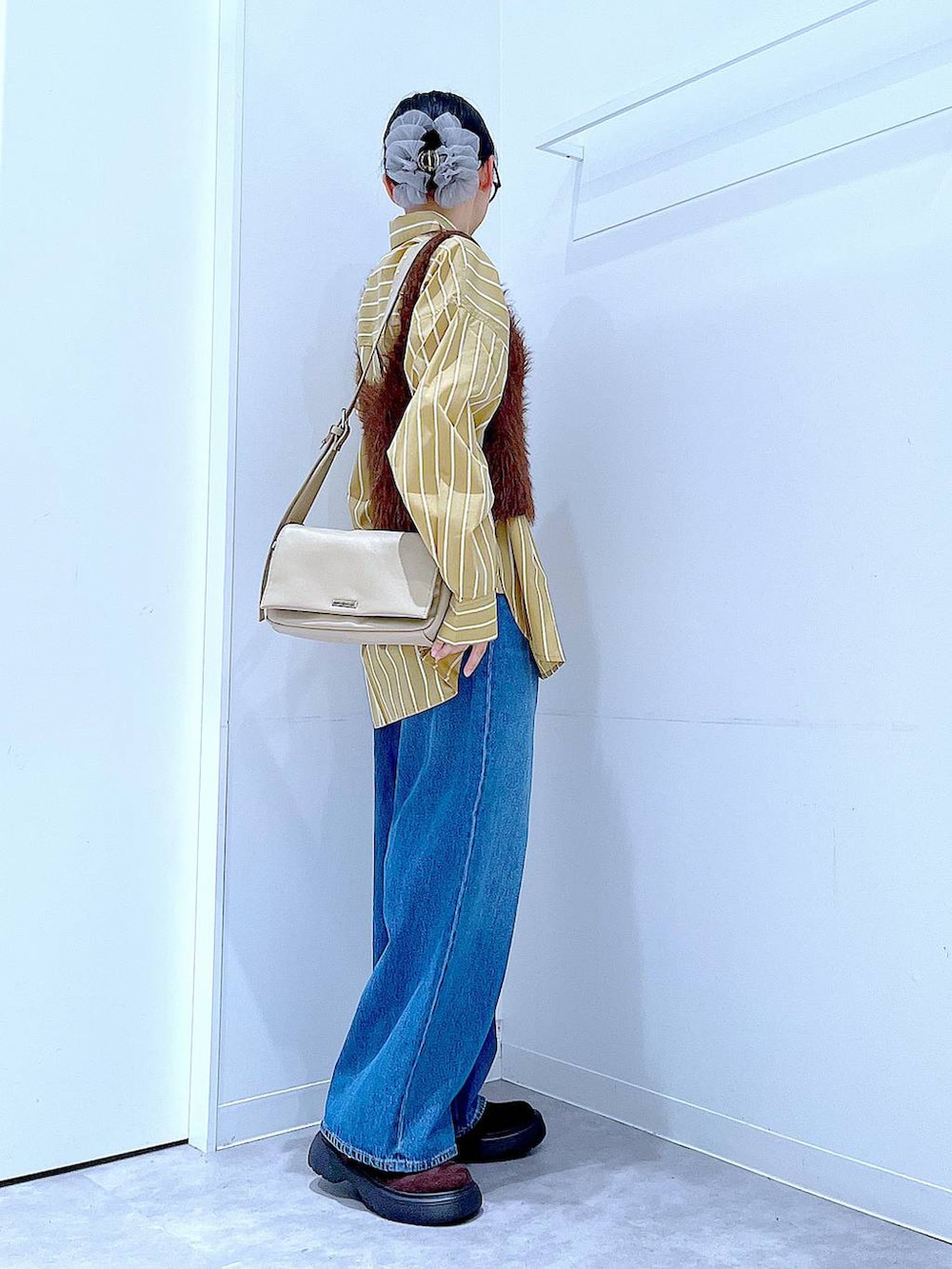 ブルー系のデニムパンツ、イエロー系のシャツ/ブラウス、ブラウン系のベストを着用したレディースの秋コーディネートの4枚目の写真