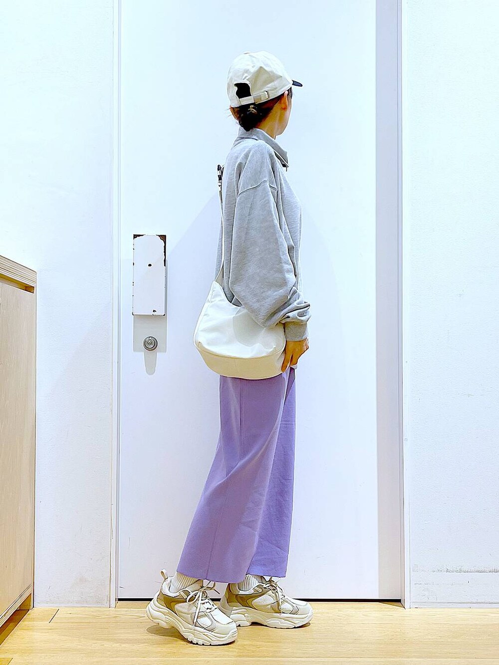 グレー系のスウェット、ベージュ系のスニーカー、ホワイト系のショルダーバッグを着用したレディースの春コーディネートの4枚目の写真