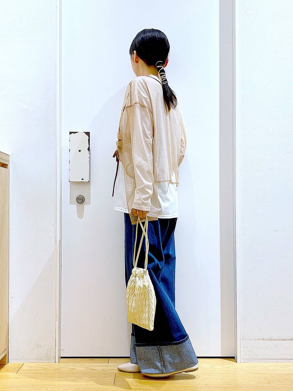 ホワイト系のショルダーバッグ、ホワイト系のパンプス、ブルー系のデニムパンツを着用したレディースの秋コーディネートの3枚目の写真