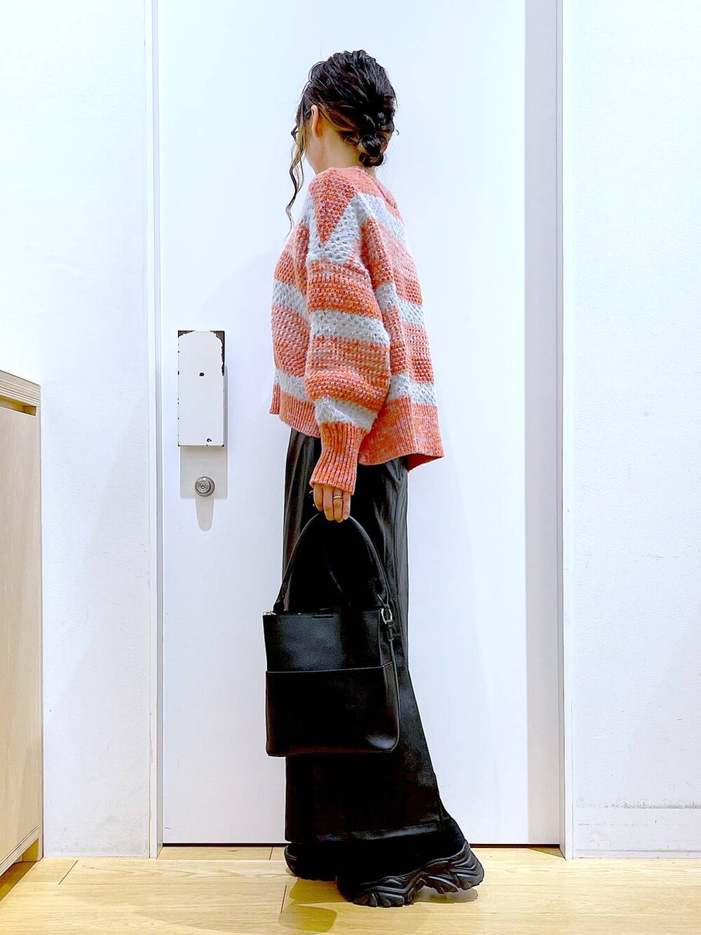 ブラック系のショルダーバッグ、ブラック系のブーツ、ブラック系のスカートを着用したレディースの冬コーディネートの3枚目の写真